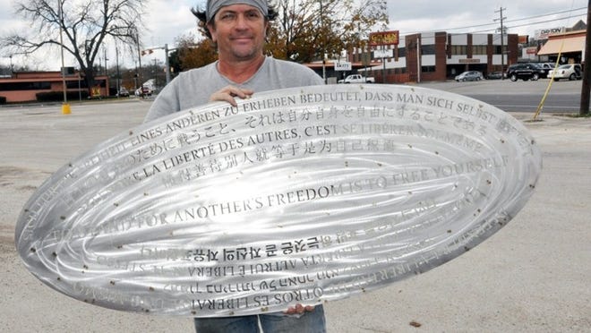 Artist Aaron Hussey displays the engraved inlay being installed at the LBJ-MLK Crossroads Memorial with the words in many languages, To Stand for Another s Freedom is to Free Yourself. Photo by Trey Hatt.
