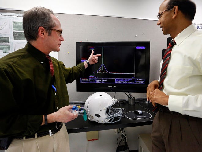 Keith Peters, MD, left, of the Department of Radiology at the University of Florida's College of Medicine, and Ghatu Subhash, right, professor of mechanical and aerospace engineering at the University of Florida's College of Engineering, show variations on a graph of the amount of impact absorbed by different helmet linings, including the traditional set of padding versus the inflatable/deflatable device they are currently researching and looking to patent, Friday, January 10, 2014, at the College of Engineering at the University of Florida.