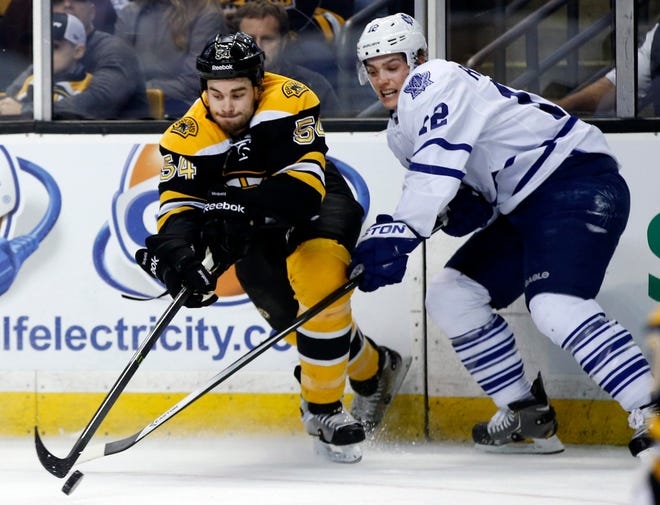 Bruins defenseman Adam McQuaid (left) and Maple Leafs left wing Mason Raymond reach to control the puck in the first period of Tuesday's game. AP Photo / Elise Amendola