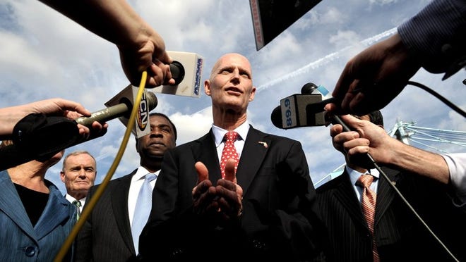 Gov. Rick Scott, center, seen hear answering questions in Jacksonville on Monday, has made no public statements regarding the problem-plagued CONNECT unemployment claims website. (AP Photo/Florida Times-Union, Bruce Lipsky)
