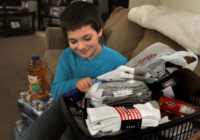 Twelve year old Christopher Adams of Riverside, NJ looks through a basket of some of the collected items (bottled water, blankets, food items, socks) for the Code Blue Shelter at the First Presbyterian Church in Delanco.