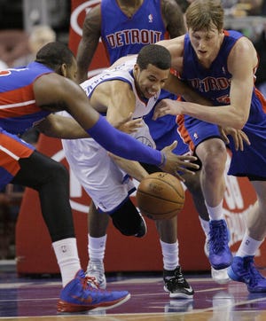 Philadelphia 76ers' Michael Carter Williams, center, and Detroit Pistons' Greg Monroe, left, and Kyle Singler, right, scramble for a loose ball under the 76ers' basket in the first half of an NBA basketball game on Friday, Jan. 10, 2014, in Philadelphia. (AP Photo/Laurence Kesterson)