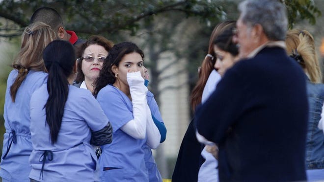 A group of employees from Doctor's Choice Medical Center on Forest Hill Boulevard gather outside the building where police say a gunman killed one person, seriously injured another and then committed suicide on Thursday, Jan. 16, 2014. (Bill Ingram/Palm Beach Post)