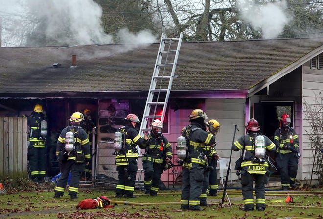 Firefighters work a house fire that sent two people to the hospital in a McKenzie Village public housing duplex in Springfield, Ore. on Thursday, January 16, 2014. (Brian Davies/The Register-Guard)