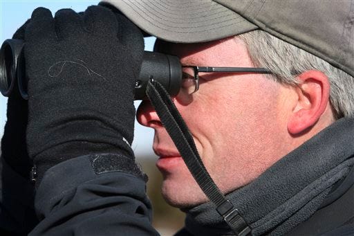 In this Jan. 1, 2014 photo, birdwatcher Neil Hayward, of Cambridge, Mass., gazes through binoculars at the Parker River National Wildlife Refuge on Plum Island, Mass. Hayward possibly set an American Birding Association record by observing 749 different birds in 2013.