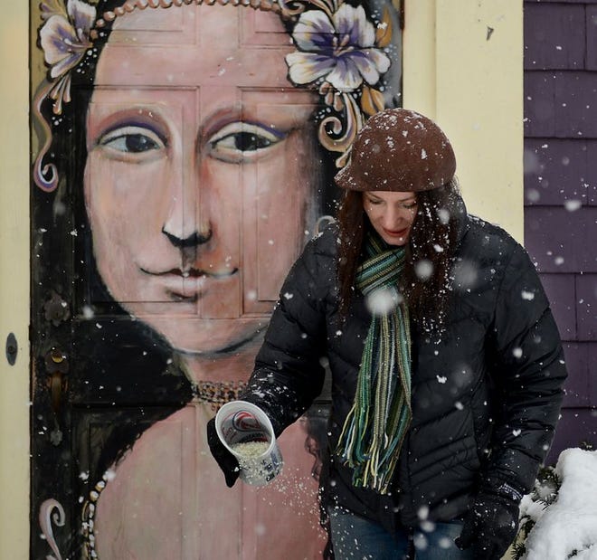 During Saturday's storm, Sue Innamorato of the Post Road Art Center in Marlborough distributes rock salt in front of the Rte. 20 frame shop's version of the Mona Lisa on the front door. The Marlborough landmark is the work of artist Bruce Collins.
