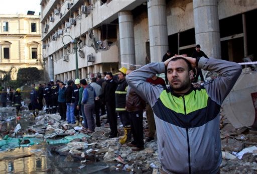 An Egyptian man stands in rubble after an explosion at the Egyptian police headquarters in downtown Cairo, Friday, Jan. 24, 2014. Three bombings hit high-profile areas around Cairo on Friday, including a suicide car bomber who struck the city's police headquarters, killing several people in the first major attack on the Egyptian capital as insurgents step up a campaign of violence following the ouster of the Islamist president. (AP Photo/Khalil Hamra)
