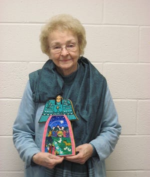 Lillian Goodwyn, a Destin resident, wears a scarf from the Market and holds an angelic nativity wall plaque from Mexico.