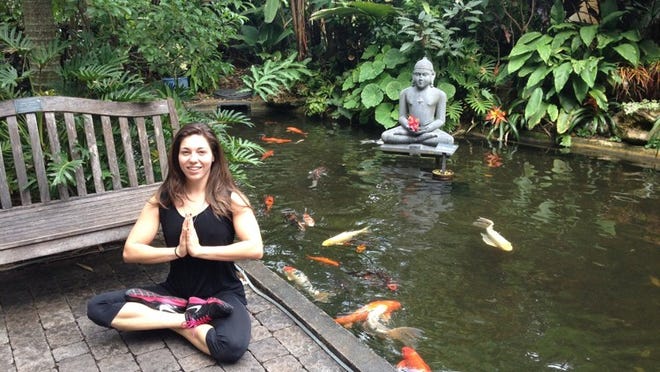 Alena Rodriguez, of Lake Worth, poses with Buddha in front of the koi pond — and does another yoga pose in front of an imposing tree. (Photo by Jan Tuckwood)