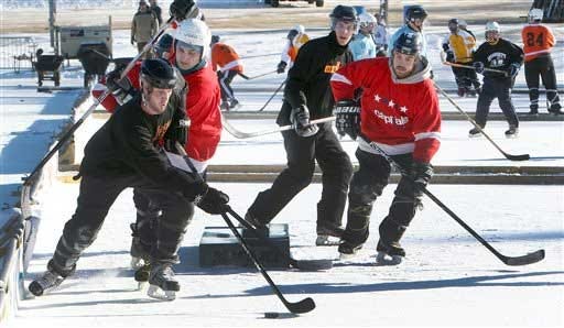 Hockey players race for the puck during the Black Ice Pond Hockey tournament Friday, Jan. 24, 2014, in Concord, N.H. More than 80 teams from around New England and Canada are competing in the three-day event.