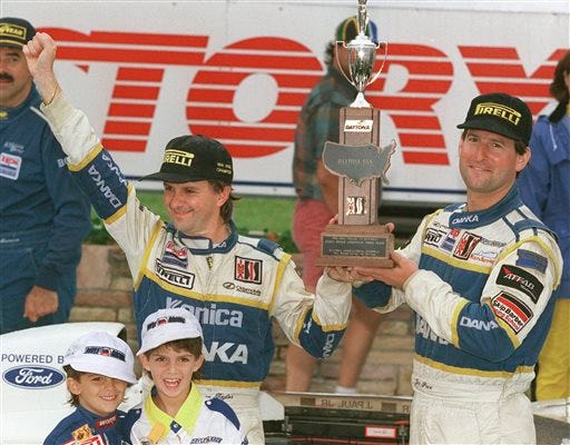 In this 1996 file photo, Wayne Taylor, top left, along with his two sons Jordan, lower left, 5, and Ricky,7, with co-driver Jim Pace celebrate winning the IMSA championship in Victory Lane at Daytona International Speedway in Daytona Beach, Fla. (AP Photo/Daytona Beach News-Journal, Nigel Cook)