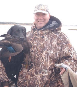 Gregg Angell, shown here, was the lone survivor of a duck hunting trip earlier this month on the Westport River. The black Labrador retriever is Logan, a friend's dog, but the duck was shot by Angell.