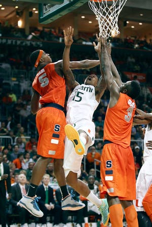 Syracuse players C.J. Fair (5) and Jerami Grant (3) block Miami's Rion Brown (15) during their game on Saturday in Coral Gables, Fla. Syracuse won 64-52.