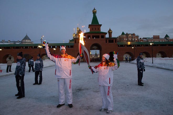 Olympic torch-bearers salute in Yoshkar-Ola, Russia, on the way to the Sochi Olympics. AP PHOTO