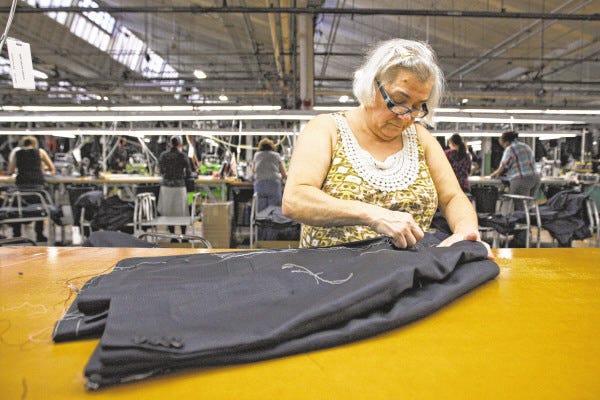 Isaura Aguiar examines and cleans coats on the manufacturing floor of Joseph Abboud.