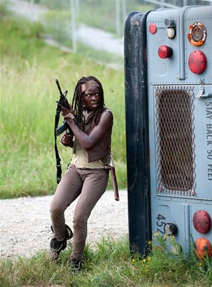 FILE - This file publicity image released by AMC shows Danai Gurira as Michonne in a scene from the series "The Walking Dead," which resumes episodes from its fourth season on Feb. 9. When she's not killing zombies on the rural Georgia set of The Walking Dead, Gurira is in Atlanta shopping for costumes for her own production or directing performances of it in Zimbabwe. (AP Photo/AMC, Gene Page)