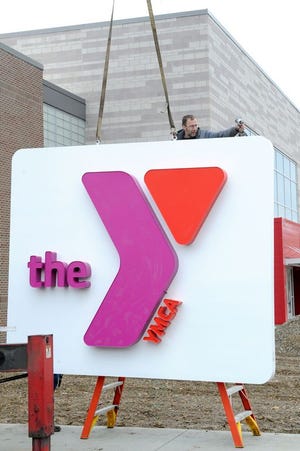 Scott Mingus of Ellet Neon Sales & Service installs a sign for the YMCA in downtown Canton.The new Eric Snow YMCA opened Monday morning.