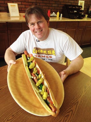 Rick Tyrrell, owner of Cheese Dawgs in Feasterville, holds one of his hot dog creations called The Beast.