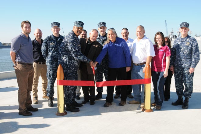 Representatives from the military, Naval Facilities Engineering Command (NAVFAC) and the construction contracting company cut the ribbon on Charlie Wharf 1 on Monday, signifying the end of the first phase of the Wharf Improvement Project to Charlie Pier. From left, Orion Marine Construction Project Manager Matt Tate, Orion Quality Control Manager Shane McCreery, COMDESRON Commodore, Capt. Ryan Tillotson, Rear Adm. Sinclair Harris, COMUSNAVSO/C4F, Orion Area Operations Manager Tony Landry, Orion Senior Vice President Dave Thornton, NS Mayport Commanding Officer, Capt. Wes McCall, NAVFAC Southeast Engineering Technician Joann Mason, Orion Superintendent Alvin Lopez, Orion Site Safety & Health Officer Robert Capelli, NAVFAC Southeast Construction Manager Chanda Comegys, NAVFAC Southeast Contracting Officer Patricia Livingstone, Mayport Public Works Officer, Cmdr. Phillip Lavallee.