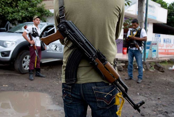 Armed men belonging to the Self-Defense Council of Michoacan stand guard Jan. 14 at a checkpoint set up by the self-defense group at the entrance to the town of Antunez, Mexico.