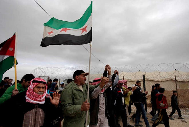 Syrian refugees chant anti-Bashar Assad slogans and wave revolutionary flags during a protest against any concessions their country's opposition may make to the Syrian government at the Geneva peace talks at Zaatari camp in Mafraq, Jordan, Tuesday, Jan. 28, 2014. (AP Photo/Mohammad Hannon)