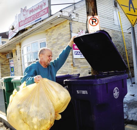 Gary Provencher of Hoaty's Restaurant on Route 1 in Hampton dumps some trash into town trash carts while discussing his view of the negative impact if the town votes to eliminate commercial trash pickup.