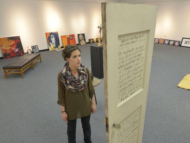 Holly Scoggins, organizer of the "One Billion Rising" art exhibit, looks at a piece by Tinia, depicting a door with messages of fear on one side and pride on the other.
