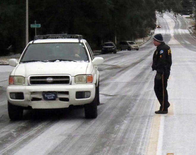Pensacola Police Sgt. Steve Bauer comes to the assistance of a motorist who made it part way up the hill on 12th Avenue and Pintado headed for Bayou Boulevard before losing traction and becoming stuck Wednesday Jan. 29, 2014, in Pensacola, Fla. In the distant background are other vehicles that became stuck and were parked or abandoned in place. (AP Photo/The Pensacola News Journal, Bruce Graner) NO SALES