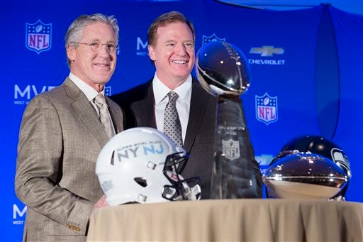 Roger Goodell, commissioner of the National Football League, center, and Pete Carroll, head coach of the Seattle Seahawks, pose for a photograph beside the Vince Lombardi and MVP trophy during a news conference at the Super Bowl XLVIII Media Center at the Sheraton hotel, Monday, Feb. 3, 2014, in New York. The Seattle Seahawks defeated the Denver Broncos, 43-8. (AP Photo/John Minchillo)