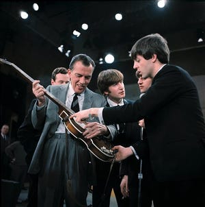 In this Feb. 9, 1964 file photo, Paul McCartney, right, shows his guitar to host Ed Sullivan before the Beatles' live television appearance on "The Ed Sullivan Show" in New York. The Beatles made their first appearance on "The Ed Sullivan Show," America's must-see weekly variety show, on Sunday, Feb. 9, 1964, officially kicking off Beatlemania.