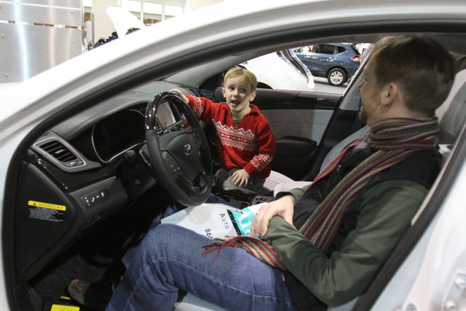 Lukas Fritsch, 5, with his father Enno Fritsch, of Providence, is interested in this Kia's DVD player Saturday at the Northeast International Auto Show in Providence.
