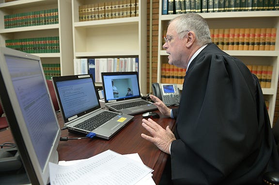 Chief district court judge Jim Roberson interviews a victim of domestic violence via a webcam to determine whether he will issue a protective order electronically in the judges' chambers at the Alamance County Civil Court building Wednesday. Photo by Sam Roberts / Times-News