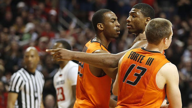 Oklahoma State's Markel Brown (22) and Phil Forte (13) hold Marcus Smart after Smart shoved a fan during a game at Texas Tech on Saturday night.