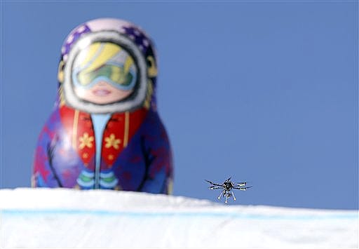 In this Friday Feb. 7 photo, a drone camera flies about the slopestyle course during a freestyle skiing slopestyle training session at the Rosa Khutor Extreme Park ahead of the 2014 Winter Olympics, Friday, Feb. 7, 2014, in Krasnaya Polyana, Russia. (AP Photo/Sergei Grits)
