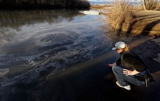 In this Wednesday, Feb. 5, 2014 photo, Amy Adams, North Carolina campaign coordinator with Appalachian Voices dips her hand into the Dan River in Danville, Va. as signs of coal ash appear in the river. Duke Energy estimates that up to 82,000 tons of ash has been released from a break in a 48-inch storm water pipe at the Dan River Power Plant in Eden N.C. Over the last year, environmental groups have tried three times to use the federal Clean Water Act to force Duke Energy to clear out leaky coal ash dumps. Each time, the N.C. Department of Environment and Natural Resources has effectively halted the lawsuit by intervening at the last minute to assert its own authority to take enforcement action. In two cases, the state has proposed modest fines but no requirement that the nation’s largest electricity provider actually clean up the coal ash ponds. The third case is pending. (AP Photo/Gerry Broome)