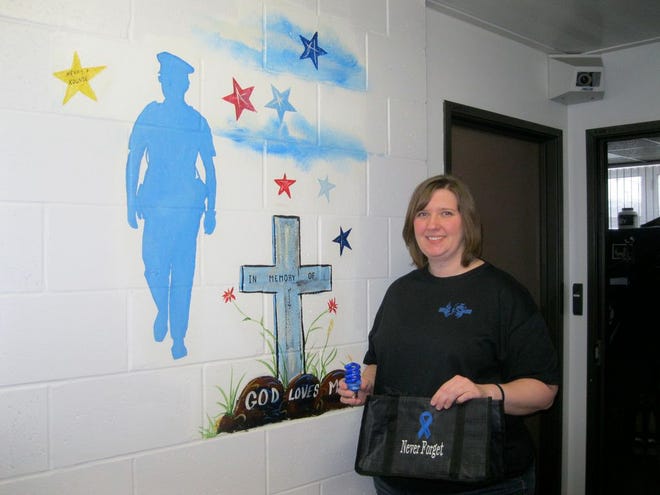East Peoria Police telecommunicator Mary Robertson holds one of the blue lights she offers on the Project Blue Light Illinois Facebook page. Residents can display the lights at their home in memory of fallen police officers.