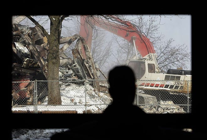 A woman inside the Massillon Senior Center watches as demolition begins on the First Merit building in downtown Massillon