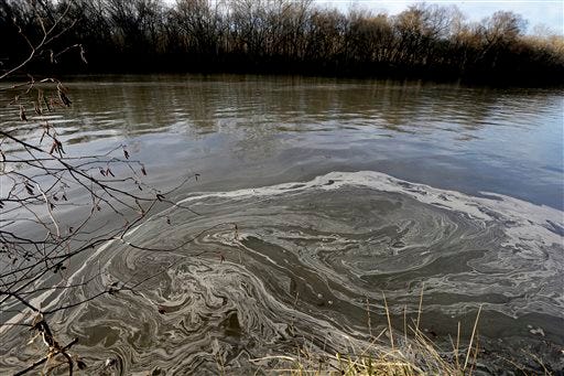In this Wednesday, Feb. 5, 2014 photo, signs of coal ash swirl in the water in the Dan River in Danville, Va. Duke Energy estimates that up to 82,000 tons of coal ash has been released from a break in a 48-inch storm water pipe at the Dan River Power Plant in Eden N.C.Over the last year, environmental groups have tried three times to use the federal Clean Water Act to force Duke Energy to clear out leaky coal ash dumps. Each time, the N.C. Department of Environment and Natural Resources has effectively halted the lawsuit by intervening at the last minute to assert its own authority to take enforcement action. In two cases, the state has proposed modest fines but no requirement that the nation’s largest electricity provider actually clean up the coal ash ponds. The third case is pending. (AP Photo/Gerry Broome)