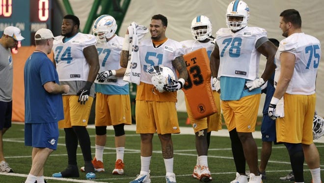 Miami Dolphins center Mike Pouncey (51) stands with guard John Jerry (74), tackle Bryant McKinnie (78) and guard Nate Garner (75) during NFL football practice, Wednesday, Nov. 6, 2013, in Davie, Fla. At left is offensive line coach Jim Turner. (AP Photo/Lynne Sladky)