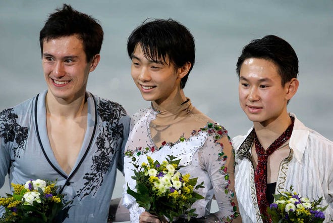 Yuzuru Hanyu of Japan, centre, Patrick Chan of Canada, left, and Denis Ten of Kazakhstan pose for photographs on the podium during the flower ceremony for the men's free skate figure skating final at the Iceberg Skating Palace during the 2014 Winter Olympics, Friday, Feb. 14, 2014, in Sochi, Russia. Hanyu placed first, Chan second and Ten third. (AP Photo/Darron Cummings)