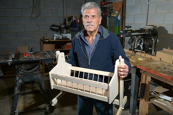 Tony Ferrita of Burlington builds doll cradles. His wife, Jane, stains them and makes the bedding and pillows. Tony, who is blind, has enjoyed working with his hands as long as he can remember. For the cradles, he uses a template and guides to assist him during construction.