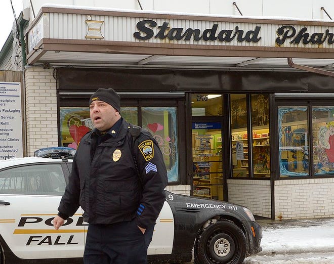 Sgt. James Smith confers with other Fall River police officers outside Standard Pharmacy after an armed robbery there Tuesday afternoon.