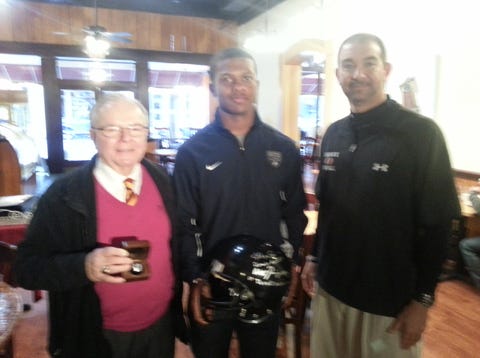 Local attorney Norm Kellum, left, received a state championship ring and an autographed helmet from Havelock football coach Jim Bob Bryant, right, and running back Derrell Scott.