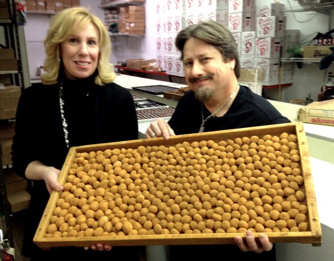 Susan Palkon, owner of Reily's Candy in Medford, and Chuck Thomas hold a freshly made flat of Irish potatoes.