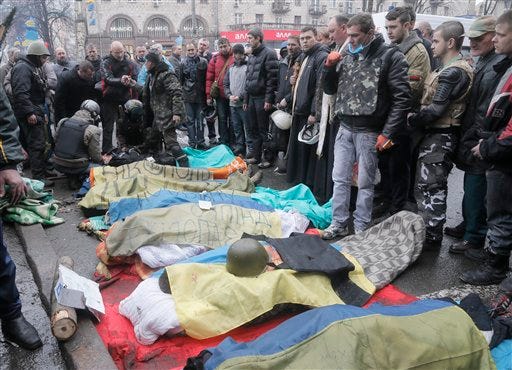 Activists pay respects to protesters who were killed in clashes with police in Kiev's Independence Square, the epicenter of the country's current unrest, Kiev, Ukraine, Thursday, Feb. 20, 2014. Fierce clashes between police and protesters, some including gunfire, shattered a brief truce in Ukraine's besieged capital Thursday, killing numerous people. The deaths came in a new eruption of violence just hours after the country's embattled president and the opposition leaders demanding his resignation called for a truce and negotiations to try to resolve Ukraine's political crisis. (AP Photo/Efrem Lukatsky)
