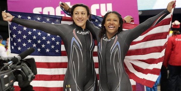 Silver medal winners Elana Meyers and Lauryn Williams, right, hold up the flag after their final run during the women's bobsled competition at the 2014 Winter Olympics, Wednesday, Feb. 19, 2014, in Krasnaya Polyana, Russia.