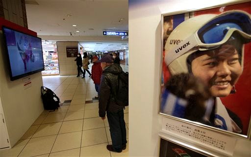 In this Wednesday, Feb. 19, 2014, photo, people watch a television showing a live broadcast of a snowboarder competing at the Sochi Winter Olympics in the women's snowboard parallel giant slalom final, in a concourse at Tokyo Station in Tokyo.