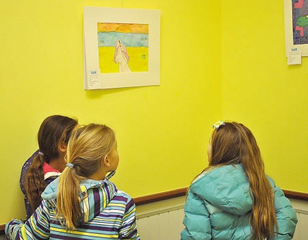 Three friends from Sacred Heart School cycle through the meeting room at The Provident Bank on Lafayette Road to view the student artwork on display.