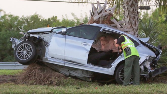 A PBSO investigator photographs a car in the median of Southern Boulevard at Marguerita Drive following an overnight wreck. Lannis Waters / The Palm Beach Post)