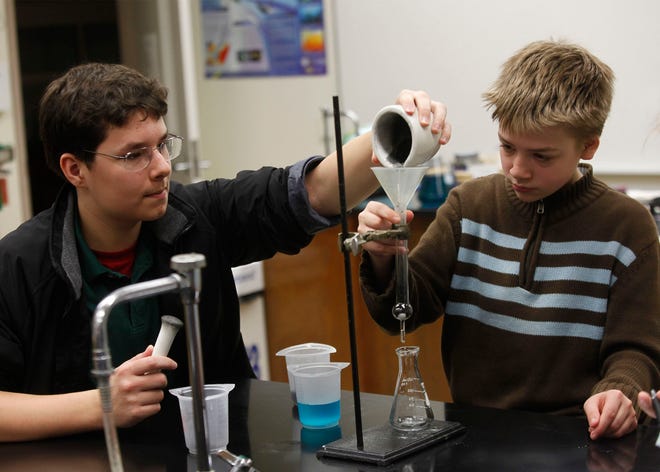 Courtland Hodges and Sean Stone, eighth graders at West Craven Middle School, experiment with the effect of water filtration.